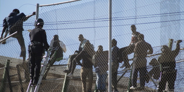 African migrants sit on top of a border fence during an attempt to cross into Spanish territories, between Morocco and Spain's north African enclave of Melilla, November 21, 2015. REUTERS/Jesus Blasco de Avellaneda