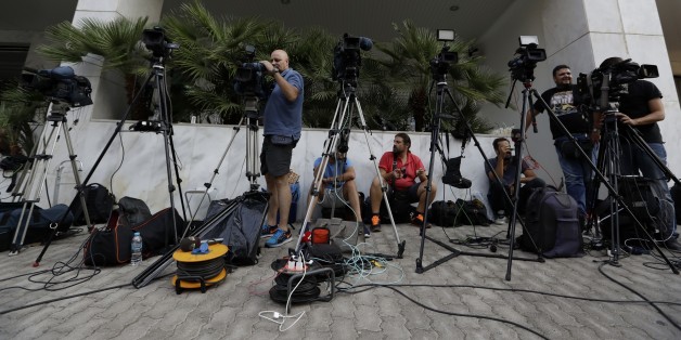 TV crews work outside the Greek Secretariat General for Media and Communication in Athens on Wednesday, Aug. 31, 2016 where eight bidders are taking part for second day in the process that would see eliminated TV stations close by the end of the year. Greece's left-wing government launched an auction Tuesday for four private national television licenses, reducing the number from seven after a heated public debate on corruption in the financially troubled country. (AP Photo/Thanassis Stavrakis)