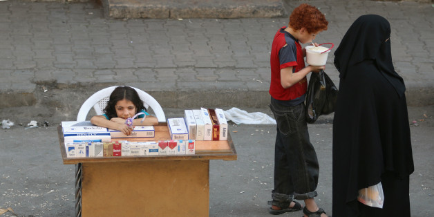 A boy eats yogurt near a girl selling cigarettes in the rebel held al-Shaar neighborhood of Aleppo, Syria, August 30, 2016. REUTERS/Abdalrhman Ismail