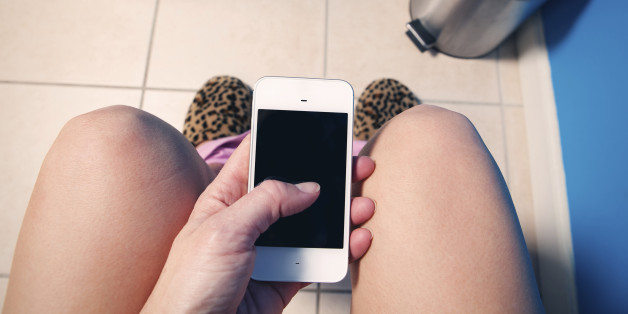 A first person view of a woman texting or scrolling her social media feed as she sits down in a restroom.