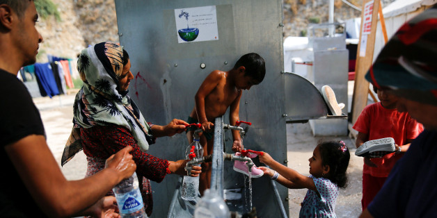 Anis, 4, from Syria (C) is bathed by his mother, as others wash their clothes and shoes, at the Souda municipality-run camp for refugees and migrants on the island of Chios, Greece, September 6, 2016. REUTERS/Alkis Konstantinidis