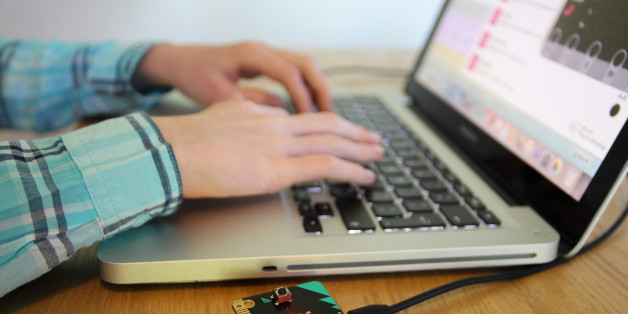Child's hands on a laptop keyboard as they code a pocked sized computing coding device at home.