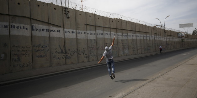 A Palestinian protester hurls stones towards Israeli troops taking positions behind the Israeli barrier during clashes in the West Bank town of Al-Ram, near Jerusalem October 22, 2015. Nine Israelis have been killed in Palestinian stabbings, shootings and vehicle attacks since the start of October. Forty-nine Palestinians, including 25 assailants, among them children, have been killed in attacks and during anti-Israeli protests. Among the causes of the turmoil is Palestinians' anger at what they see as Jewish encroachment on the al-Aqsa mosque compound in Jerusalem's walled Old City. REUTERS/Mohamad Torokman
