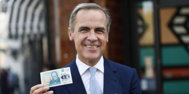 Bank of England governor Mark Carney poses with a new polymer five pound note at Whitecross Street Market in London, Britain September 13, 2016. REUTERS/Stefan Wermuth