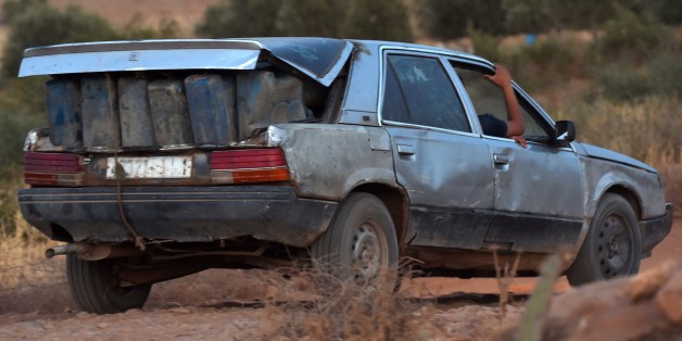 Smugglers drive carrying empty containers to be filled with oil in Algeria before smuggling them back into Morocco on August 22, 2014 near the Moroccan city of Oujda along the Moroccan-Algerian border. 20 years after the border was closed, its reopening seems more distant than ever despite the economic damage with Algeria having trenches to prevent fuel smuggling on one side of the border and Moroco building a fence against 'terrorism' on the other. AFP PHOTO