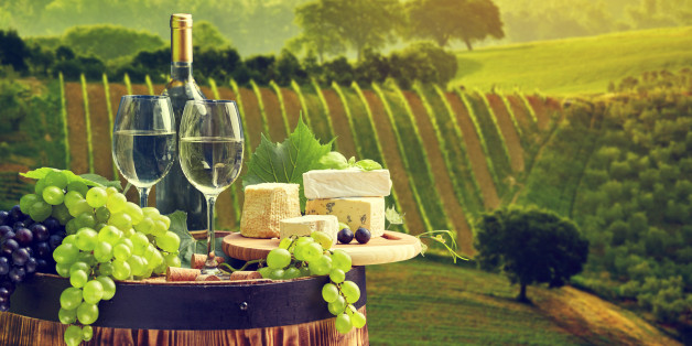 White wine bottle and wine glass on wodden barrel. Beautiful Tuscany background