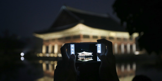 A visitor takes a photograph of Gyeonghoeru pavilion, a part of Gyeongbok palace, during the evening in central Seoul May 23, 2013. Gyeongbok Palace offered late-night admissions to the public from Wednesday until Sunday, The Cultural Heritage Administration said. REUTERS/Kim Hong-Ji (SOUTH KOREA - Tags: TRAVEL)