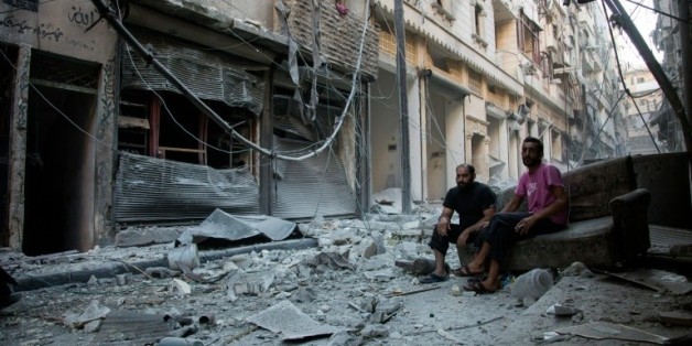 Des Syriens au milieu des décombres du quartier pro-gouvernemental de Karm al-Jabal ciblé par une frappe aérienne le 18 septembre 2016 à Alep