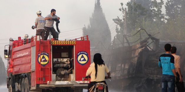 Des membres de la sécurité civile luttent contre les flammes qui dévorent un convoi d'aide humanitaire près de la ville d'Alep, dans le nord de la Syrie
