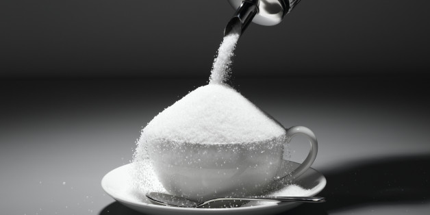 Sugar being poured into tea cup, close-up