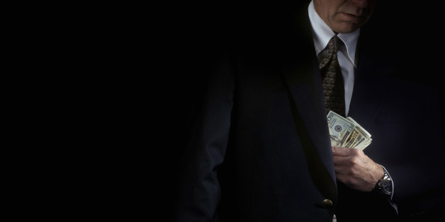 Mature businessman hiding money in his pocket