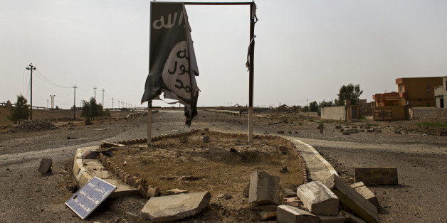 In this Sunday, August 28, 2016 photo, a partially destroyed Islamic State group banner hangs at the entrance to Qayara, Iraq. The skies above Qayara are black with the smoke from more than a dozen oil wells set alight by Islamic State group fighters attempting to obstruct airstrikes as Iraqi forces pushed into the the town on bank of the Tigris last week and took control of the entire area Thursday. (AP Photo/Susannah George)