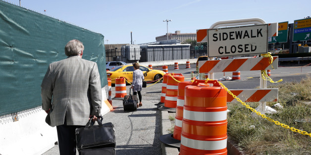 In this Wednesday, Aug. 24, 2016, photo, arriving passengers haul their suitcases down a pathway toward temporary taxi stand outside of Terminal B at LaGuardia Airport in New York. Since Monday's traffic congestion debacle, Port Authority officials and others participating in the airport's $4 billion renovation, are trying to cope with traffic congestion that has impacted travelers trying to get to and from the airport. (AP Photo/Kathy Willens)