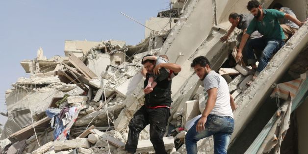 Un habitant évacue un enfant des décombres d'un immeuble après des raids aériens, le 21 septembre 2016 à Alep, en Syrie