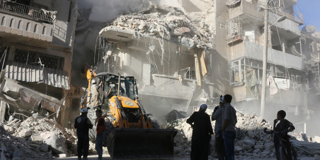 Civilians watch as a tractor clears the rubble following Syrian government forces airstrikes in the rebel held neighbourhood of Tariq a-Bab in Aleppo on September 24, 2016. Residents in Syria's battleground city of Aleppo cowered indoors as fierce air strikes toppled buildings and killed at least 52 civilians, after diplomatic efforts to revive a ceasefire failed. / AFP / THAER MOHAMMED (Photo credit should read THAER MOHAMMED/AFP/Getty Images)