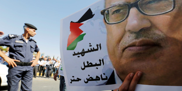 A Jordanian police officer stands guard next a picture of Jordanian writer Nahed Hatter, who was shot dead, during a sit-in in front of the prime minister's building in Amman, Jordan, September 26, 2016. REUTERS/Muhammad Hamed