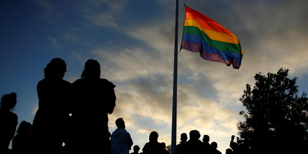 Mourners gather under an LGBT pride flag flying at half-mast for a candlelight vigil in remembrance for mass shooting victims in Orlando, from San Diego, California, U.S. June 12, 2016. REUTERS/Mike Blake