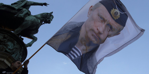 A man waves a flag showing Russian President Vladimir Putin in front of the monument of late Serbian Duke Mihailo Obrenovic, during a meeting to show their support for a referendum in Republika Srpska, in Belgrade, Serbia, Saturday, Sept. 24, 2016. Bosnia's Serb mini-state is holding a referendum this weekend that has turned into a proxy political battle between the West and Russia, stoking ethnic tensions and triggering fears of new clashes more than 20 years after the end of the Balkans War. (