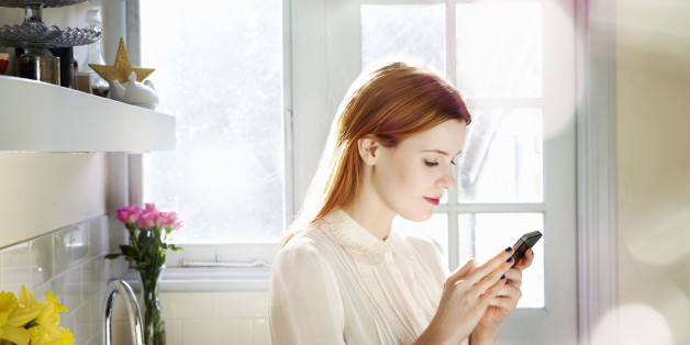 woman texting on mobile in kitchen
