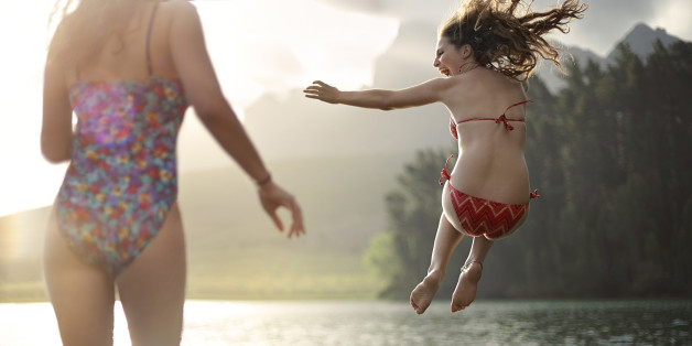2 girls jumping into a lake