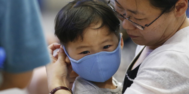 A passenger puts a masks on her son to prevent contracting Middle East Respiratory Syndrome (MERS) at the Incheon International Airport in Incheon, South Korea, June 14, 2015. A South Korean hospital suspended most services on Sunday after being identified as the epicentre of the spread of a deadly respiratory disease that has killed 15 people since being diagnosed in the country nearly four weeks ago. REUTERS/Kim Hong-Ji
