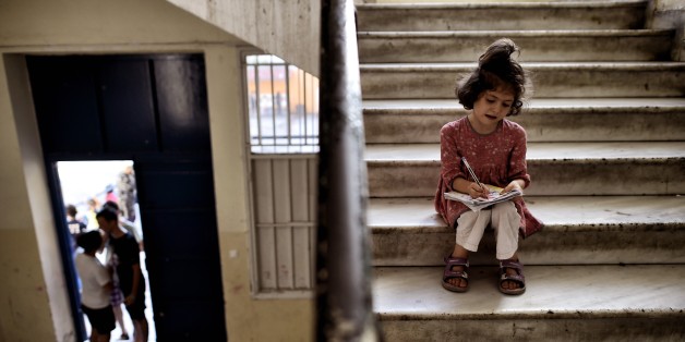 A young girl drawsas she sits in the stairs of an abandoned school used by volunteers for hosting Syrian and Afghan refugees in Athens on July 1, 2016.
Some 250 people live in self-management in the school of Athens city center, closed for three years. The families occupy three floors of the building, and twenty classrooms, where a tense sheets forest delineate areas of life and protect privacy. The squat was established in mid-March, when the sudden closure of their borders with the countries north of Greece makes it a trap for those who relied only cross to reach Germany or Sweden. Almost all e now living in dozens of camps set up in haste by the government. Some rent rooms. The others are squat. The government estimates about 1,500 the number of people living well into 'outdoor hospitality structures.' / AFP / ARIS MESSINIS (Photo credit should read ARIS MESSINIS/AFP/Getty Images)