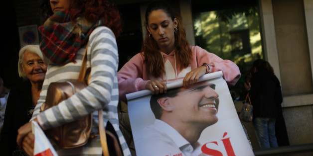 A woman rolls up a poster with the photograph of Spain's Socialist party leader Pedro Sanchez outside the party headquarters in Madrid, Saturday, Oct. 1, 2016. Spain's Socialist party is facing strong internal discord as they vote to decide if they will keep or oust their leader Pedro Sanchez, who has been leading opposition to acting conservative Prime Minister Mariano Rajoy's efforts to build a minority government and end a nine-month political deadlock. (AP Photo/Francisco Seco)