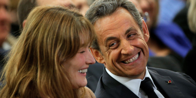 Former French President Nicolas Sarkozy, right, and his wife, Carla Bruni-Sarkozy, smile, during a meeting for the leadership of the conservative UMP party, in Paris, Friday, Nov. 7, 2014. Sarkozy, who drifted into the political wilderness after losing to Hollande in 2012, is seeking the leadership of the conservative UMP party. (AP Photo/Thibault Camus)