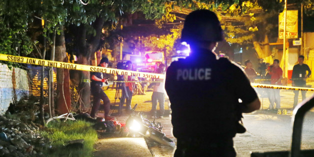 In this Friday, Sept. 23, 2016 photo, a police SWAT member stands guard as police operatives examine the scene where two bodies lay on a road after being killed in a police drug "buy-bust" operation before dawn in Pasig city, east of Manila, Philippines. Philippine President Rodrigo Duterte said on Thursday he will invite the U.N. chief and European Union officials to investigate his bloody anti-drug crackdown, but only if he can question them in public afterward to prove their human rights concerns are baseless. More than 3,000 suspected drug dealers and users have been killed since July and more than 600,000 others have surrendered for fear of being killed in Duterte's crackdown. Despite growing alarm, Duterte said he won't stop the campaign.(AP Photo/Bullit Marquez, File)