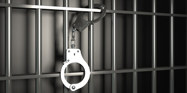 metal prison bars with handcuffs on black background