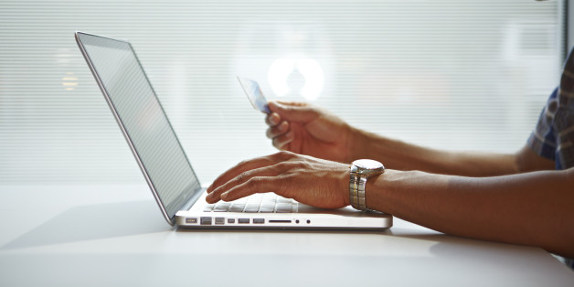 African american male arms hold credit card as he makes an online internet purchase with his laptop computer using e-commerce