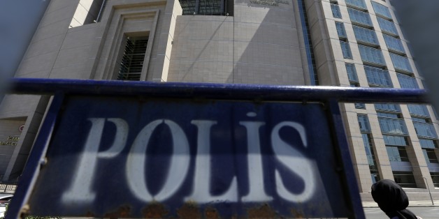A woman enters a courthouse as a police fence is on display outside the building in Istanbul, on Monday, Aug. 15, 2016. Turkey's state-run news agency says police teams are conducting operations at three Istanbul courthouses as part of an investigation into the July 15 abortive coup. (AP Photo/Thanassis Stavrakis)