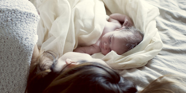 New born baby and mother resting in bed