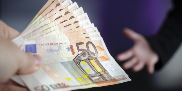 Berlin, Germany - August 03: In this Photo Illustration a person hand over Euro bills to another person on August 03, 2016 in Berlin, Germany. (Photo Illustration by Thomas Trutschel/Photothek via Getty Images)