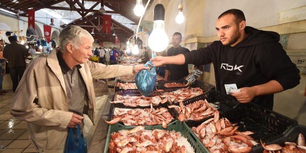A fish vendor sells his goods to a customer in the central market of Tunisia on October 23, 2014. AFP PHOTO / FADEL SENNA (Photo credit should read FADEL SENNA/AFP/Getty Images)