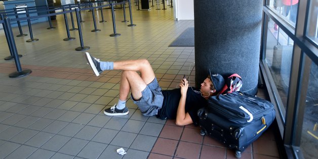 Traveller Santiago Aldrete, who arrived from Bali and is awaiting his flight to Mexico City, gets comfortable on the ground while charging his phone at Los Angeles International Airport on July 1, 2016 where a record 1.207 million people are expected to pass through during their travels over the Fourth of July weekend. LAX officials said the number of travelers anticipated to use the airport is up 9.7 percent from last year's record 1.1 million people over the holiday travel period, which runs f