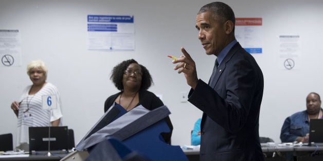 Poll workers look on as US President Barack Obama (C) gestures towards the press as he votes early at the Cook County Office Building in Chicago, Illinois, October 7, 2016.Obama cast an early ballot on Friday, highlighting a Democratic drive to get voters to the polls even before November 8. During an unannounced visit, Obama stood before a voting machine at the Chicago Board of Elections office, punched in his choice and smirked when asked who he had voted for. / AFP / JIM WATSON (Photo