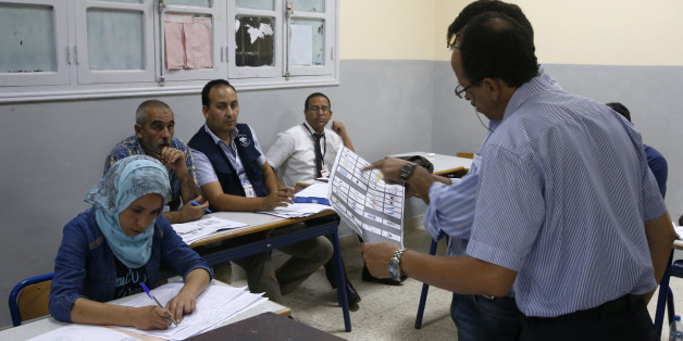 The president of a polling station shows a ballot as officials and political party's representatives count the ballots as from left to right observers Moroccan Omar Eloufir from Moroccan League for Citizenship and Law Man, second left, Tunisian Mouldi Ayari from Election Network in the Arab Region and Moroccan Ahmed Bazzi from National Observatory of voter rights second right , back, looks on in the polling station in Rabat, Morocco, Friday, Oct. 7, 2016. Amid worries about jobs and extremism,
