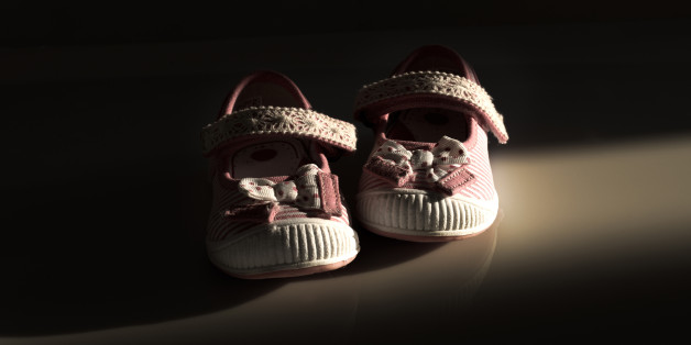 Conceptual image of violence to kids represented with a pair of baby shoes on a dark background