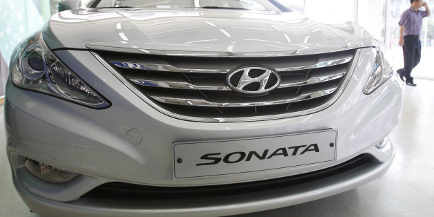 An employee walks past Hyundai Motor's Sonata, on display at the automaker's dealership in Seoul September 1, 2011. South Korea's Hyundai Motor stretched its current winning streak in August with global sales climbing 5 percent, driven by strong shipments from its overseas plants in China, India and the United States. REUTERS/Truth Leem (SOUTH KOREA - Tags: TRANSPORT BUSINESS)