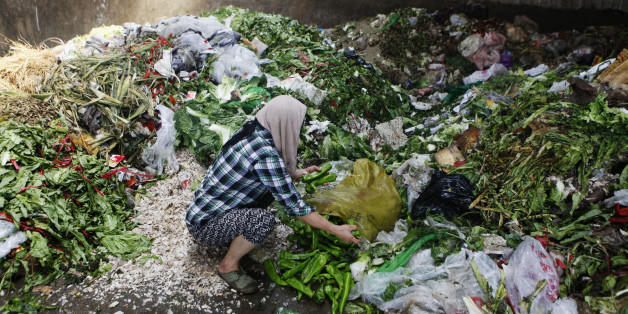 A woman picks up vegetables discarded by food vendors at a garbage dump site of a wholesale market in Xi'an, Shaanxi province July 27, 2014. About 60 tonnes of vegetables are discarded every day in the market due to damages mainly caused by hot weather. Many residents come to pick them up at a garbage dump site to eat or feed their livestock, local media reported. Picture taken July 27, 2014. REUTERS/Stringer (CHINA - Tags: SOCIETY FOOD) CHINA OUT. NO COMMERCIAL OR EDITORIAL SALES IN CHINA