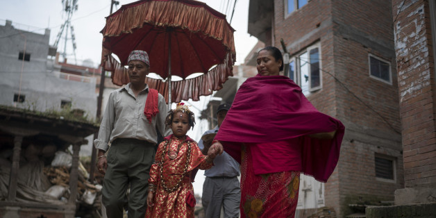 BHAKTAPUR, NEPAL - OCTOBER 07: The Kumari priest and his wife escort Jibika Bajracharya, the newly appointed child goddess Kumari, through the streets on October 7, 2016 in Bhaktapur, Nepal. The Bhaktapur Kumari is a living child goddess and is an ancient tradition in Kathmandu Valley as devotees worship the newly appointed child goddess in order to receive blessings from ancestors or deities. As the new Kumari of Bhaktapur, Jibika Bajracharya performs her role in public during the 15-day long D