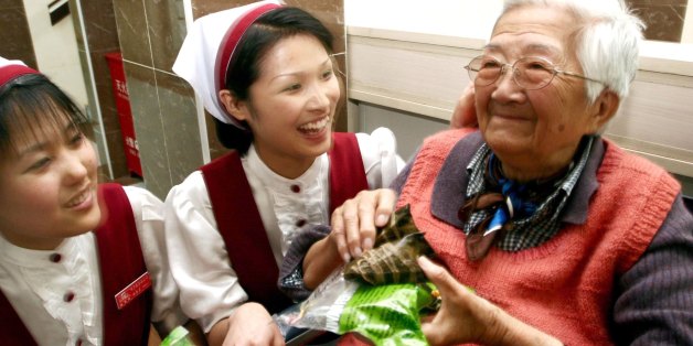 NANJING, CHINA - MAY 31, 2006: (CHINA OUT) Beijing Weiduomei Foods Co. Ltd. present zongzi to an eldery member of the Welfare Institution on May 31, 2006 in Nanjing, China . May 31 is the Chinese traditional Dragon boat festival which is one of three major Chinese holidays, along with the Spring and Moon Festivals. Of the three, it is possibly the oldest, dating back to the Warring States Period in 227 B.C. The festival commemorates Qu Yuan, a minister in the service of the Chu Emperor. Despairing over corruption at court, Qu threw himself into a river. Townspeople jumped into their boats and tried in vain to save him. Over the years, the story of Qu's demise transformed into the traditions of racing dragon boats and eating zongzi, a kind of rice wrapped in bamboo leaves. (Photo by VCG via Getty Images)