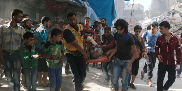 TOPSHOT - Syrians carry the body of a man following air strikes on the rebel-held Fardous neighbourhood of the northern embattled Syrian city of Aleppo on October 12, 2016. / AFP / AMEER ALHALBI (Photo credit should read AMEER ALHALBI/AFP/Getty Images)