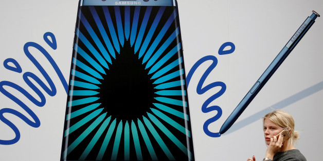 A woman speaks on an Apple phone as she passes an advert for the Samsung Galaxy Note 7 in London, Britain, September 2, 2016. REUTERS/Luke MacGregor/File Photo