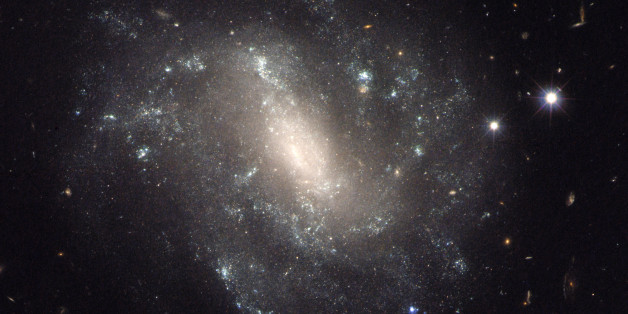 This image provided by NASA shows a barred spiral galaxy 130 million light-years away and is one of the measurements that astronomers used to come up with a faster rate of expansion of the universe. And if that new rate is correct, then scientists have to refigure some basic assumptions about the cosmos. (NASA via AP)