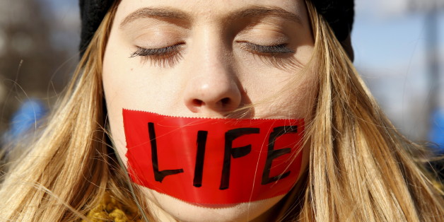 A protester with her mouth taped over with the word "life" stands in front of the U.S. Supreme Court on the morning the court takes up a major abortion case focusing on whether a Texas law that imposes strict regulations on abortion doctors and clinic buildings interferes with the constitutional right of a woman to end her pregnancy, in Washington March 2, 2016. REUTERS/Kevin Lamarque TPX IMAGES OF THE DAY