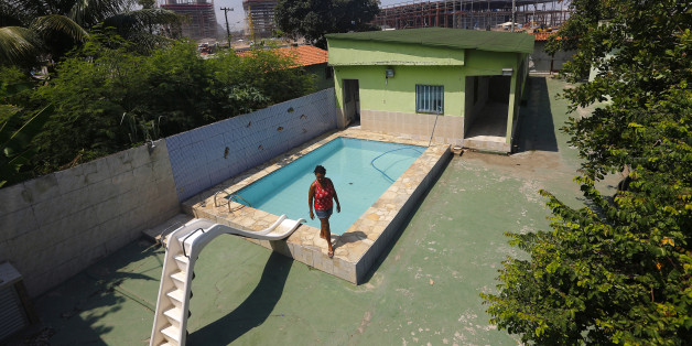 Marcias Lemos, 57, walks by a pool in her house, with cranes and construction work for the Rio 2016 Olympic Park seen in the background, at the Vila Autodromo favela in Rio de Janeiro January 28, 2015. Street addresses jump in the Vila Autodromo favela: 39, 42, 48, 51. The missing numbers belonged to homes now reduced to rubble to make way for the Olympic Park in Rio de Janeiro. But 18 months before the Olympic Games begin, about 50 families still refuse to leave, clinging on despite increasing