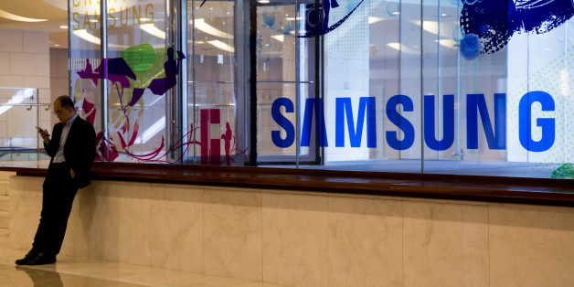 A man uses a mobile device in front of Samsung Electronics Co. signage at the company's D'light flagship store in Seoul, South Korea, on Wednesday, Oct. 12, 2016. Samsung halted sales of its Galaxy Note 7 smartphones and asked consumers to stop using the ones they've already purchased, another blow to South Korea's largest company as it struggles with a crisis over exploding batteries. Photographer: SeongJoon Cho/Bloomberg via Getty Images