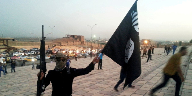 A fighter of the Islamic State of Iraq and the Levant (ISIL) holds an ISIL flag and a weapon on a street in the city of Mosul, Iraq June 23, 2014. To match Insight MIDEAST-CRISIS/MOSUL-ISLAMIC STATE REUTERS/Stringer/File Photo